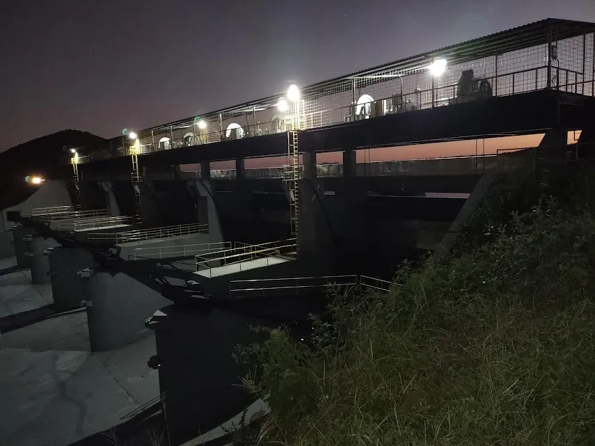Vertedouro da Barragem de Banabuiú fotografado à noite, com as luminárias da passarela de manobra acesas sobre as comportas.