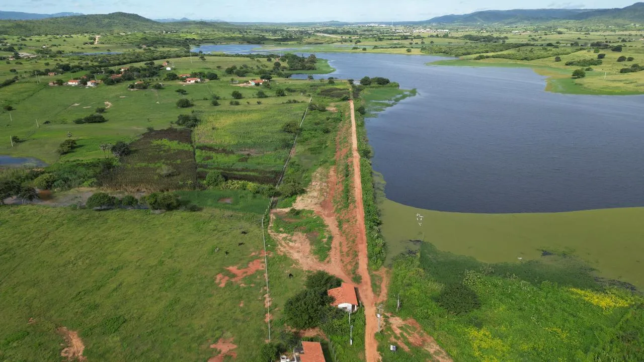 Vista aérea do açude de Angicos com o maciço de terra atravessando a imagem e área rural verde ao redor.